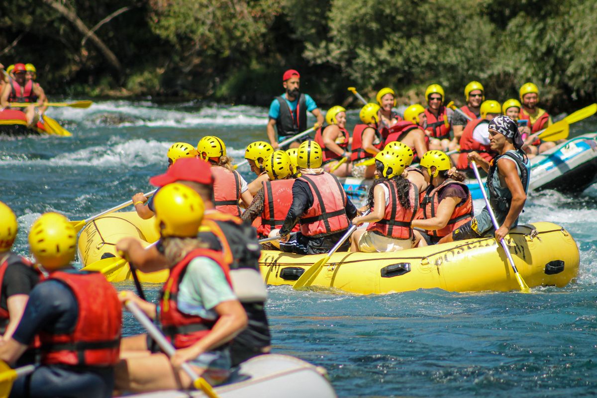 Grupa u gumenom čamcu na raftingu, s kacigama